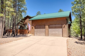 A log cabin with a green roof, two garage doors, and an American flag.
