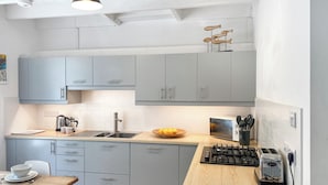 A modern kitchen with grey cabinets, a wooden countertop, a gas stove, and a kettle. - 3 bedroom accommodation in St Ives (St Ives)