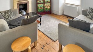 A living room with a fireplace, a television, and a cabinet with artwork. - 3 bedroom accommodation in St Ives (St Ives)