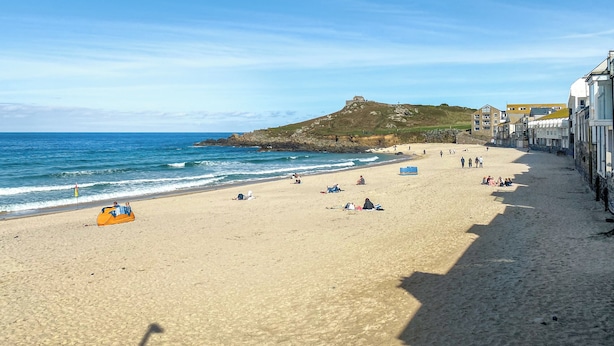 A beach with clear skies, a sandy shore, and buildings along the coastline. - 3 bedroom accommodation in St Ives (St Ives)