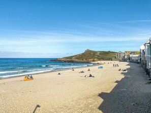 Une plage avec un ciel dégagé, un rivage sablonneux et des bâtiments le long de la côte.
