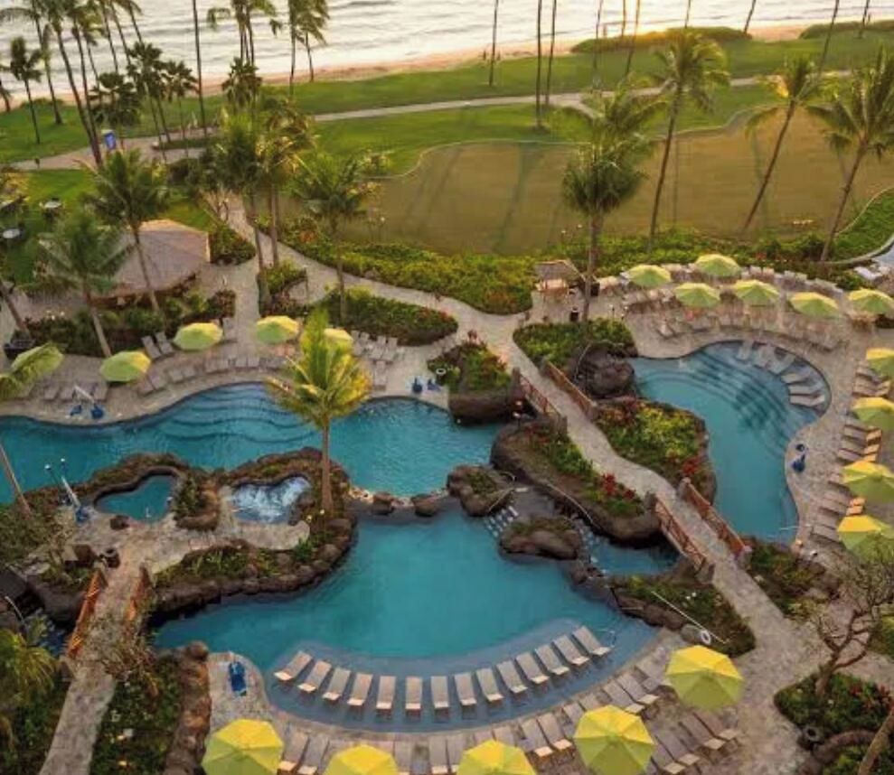 A resort with multiple swimming pools, palm trees, and sun loungers.