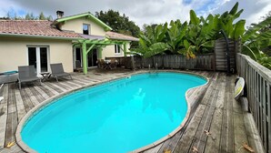 A backyard with a swimming pool, wooden deck, and a covered patio area. - In the countryside near the beach (Saint-Barthelemy)