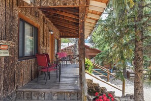 A wooden cabin with a porch, outdoor seating, and a warning sign. - 3 bedroom accommodation in Red River (Red River)