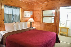 Una camera da letto in legno con un letto, un comodino, una lampada e una finestra.