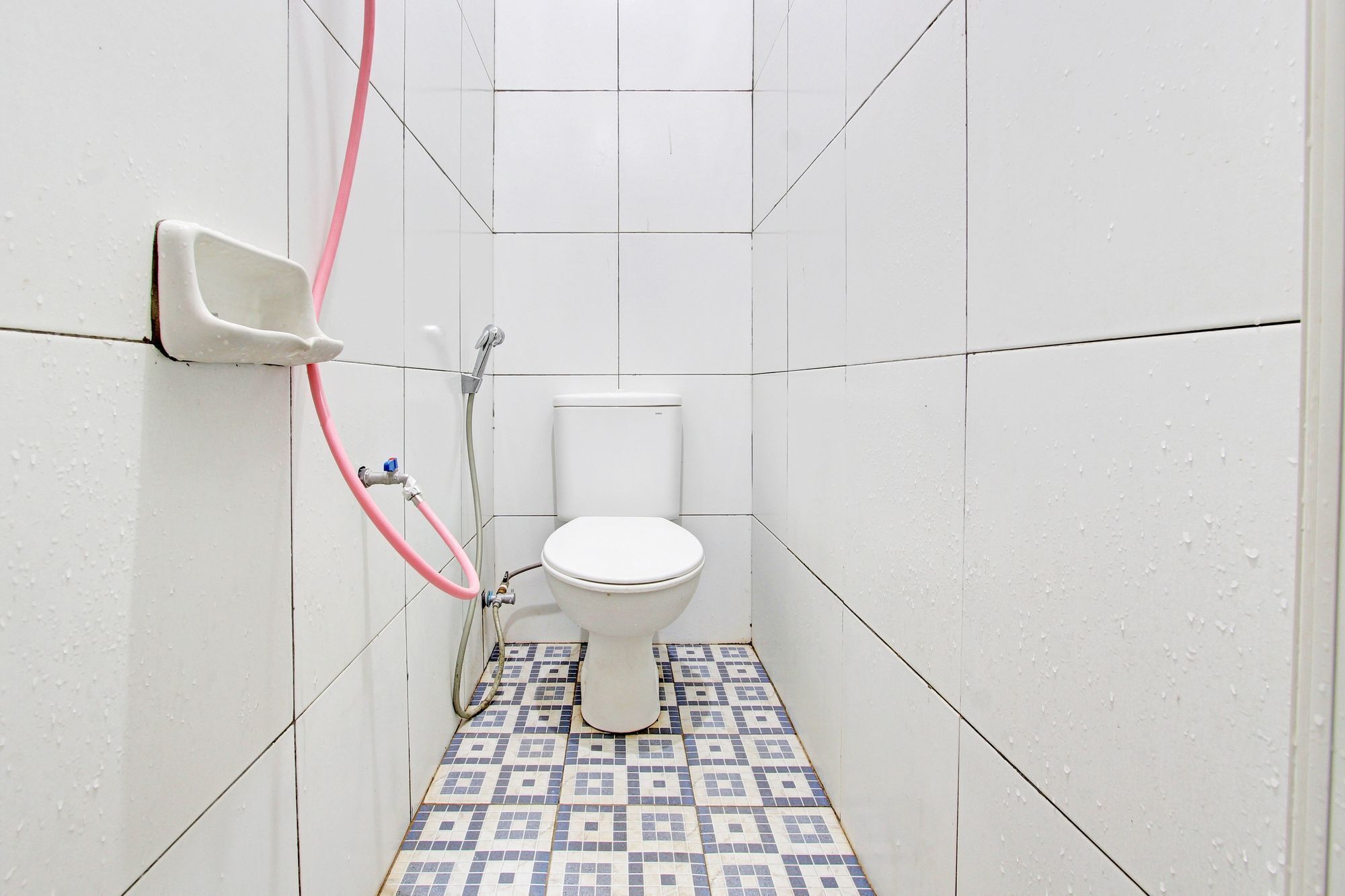 A small, tiled bathroom with a toilet, a shower, and a hand dryer.