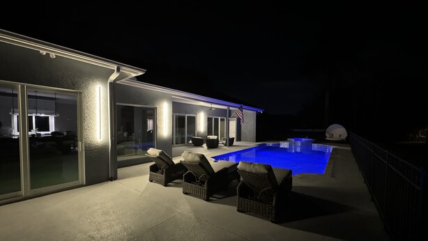 A modern house with a swimming pool, outdoor seating, and a large glass door leading to a dining area. - Fall In Naples - Game Room Pvt Pool Hot Tub Impeccable Decor 3 Bedroom Home (Naples)