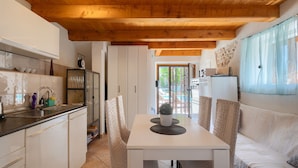A compact kitchen with a white countertop, a sink, and cabinets. There's a dining area with a white table and a sofa.