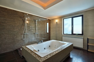 Un baño moderno con una bañera grande, zona de ducha y ventana que proporciona luz natural.
