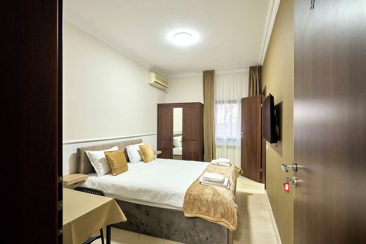Une chambre d’hôtel équipée d’un lit, d’une table de chevet, d’une télévision, d’une armoire et d’un appareil de climatisation.