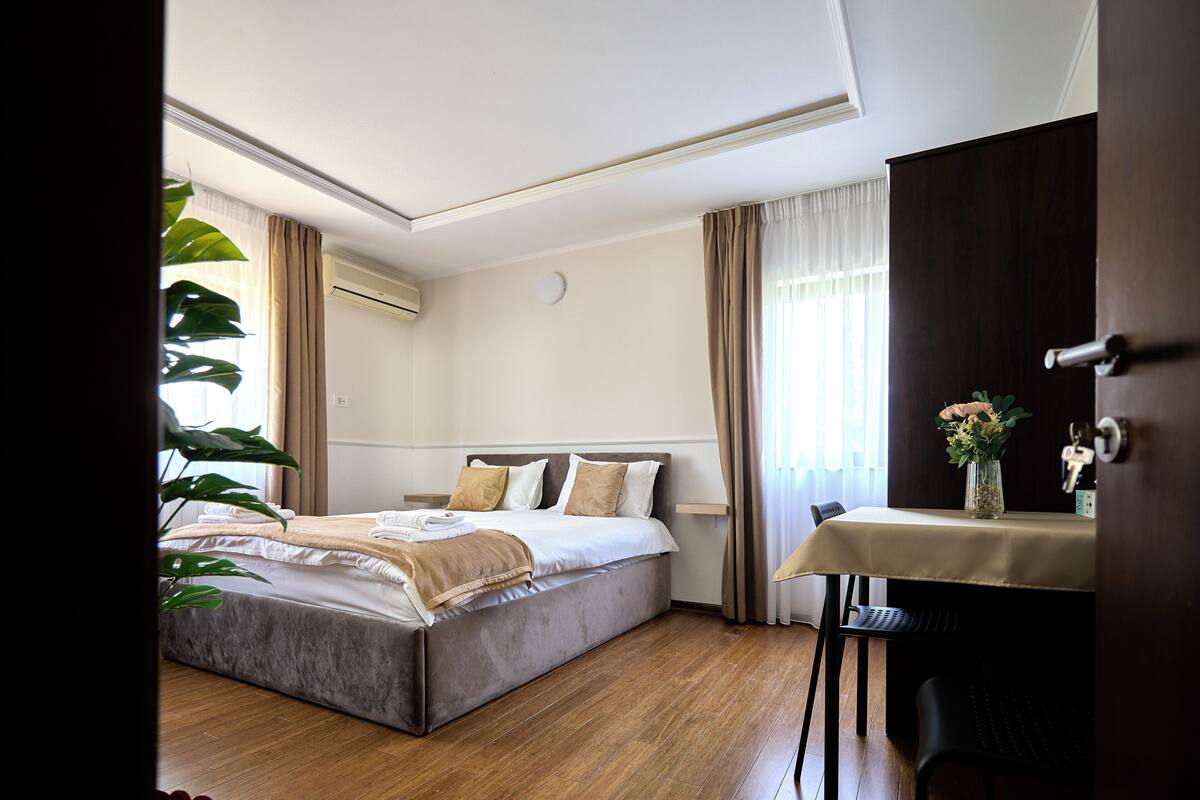 Une chambre à coucher avec un lit, une table de chevet et une fenêtre avec des rideaux.