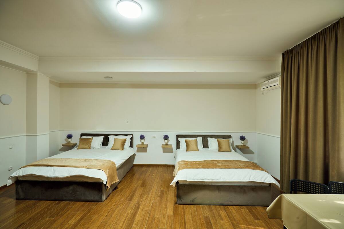 Une chambre d’hôtel avec deux lits, une petite table, une chaise et un appareil de climatisation.