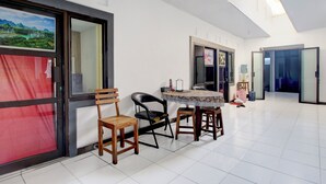 A spacious room with a dining area featuring a round table and chairs, a large window with a view of a mountainous landscape, and a door leading to another room. - Hotel O Kd House (Semarang)