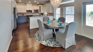 Una cocina moderna con armarios blancos, una isla central y un comedor con candelabro.