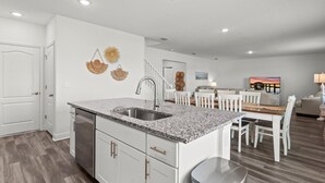 A modern kitchen with granite countertops, white cabinetry, and a stainless steel sink. - Turtle Paradisena | Spacious Home Just One Block From the Beach! (Daytona Beach)