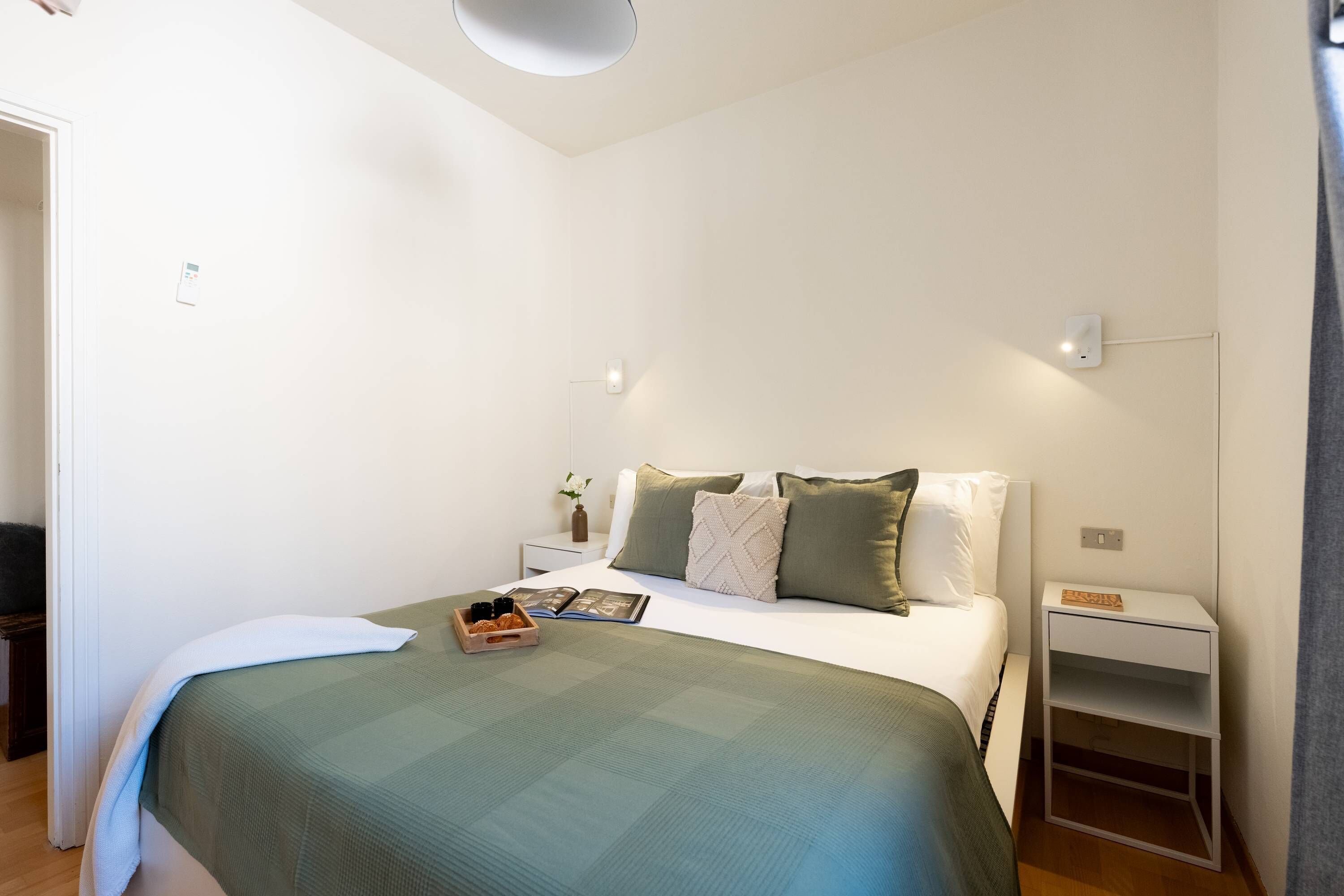Une chambre à coucher bien rangée, avec un lit, des tables de chevet et une petite table de nuit.