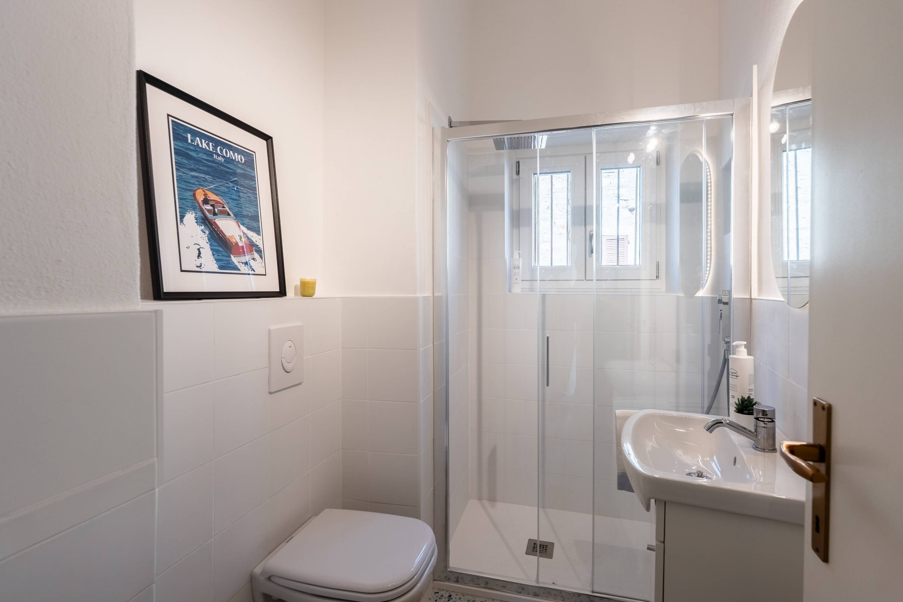 A modern bathroom with a glass shower enclosure, a white toilet, and a sink with a mirror.