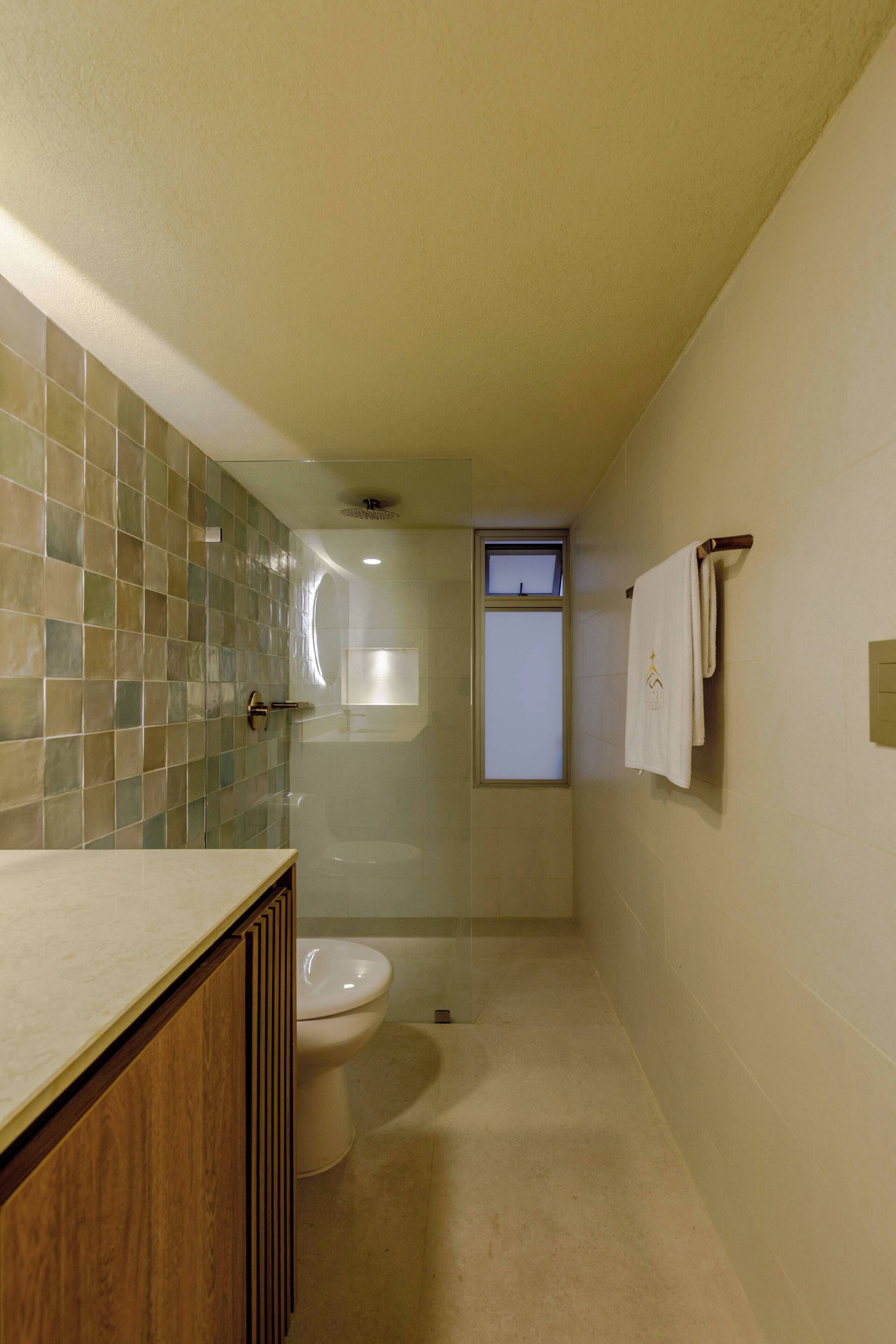A bathroom with a tiled shower, a toilet, and a sink with wooden cabinets.