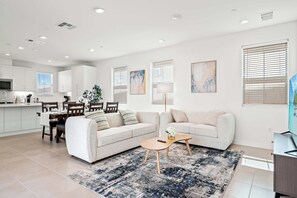 A modern living room with a sofa, coffee table, and a dining area with chairs and a table. - Stylish 3BR Oasis in Palm Desert Near El Paseo Zoo (Palm Desert)