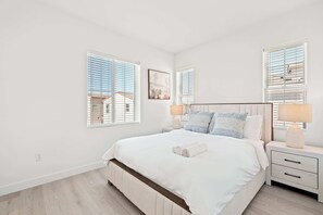 Un dormitorio con una cama grande, dos mesitas de noche y una ventana con persianas.