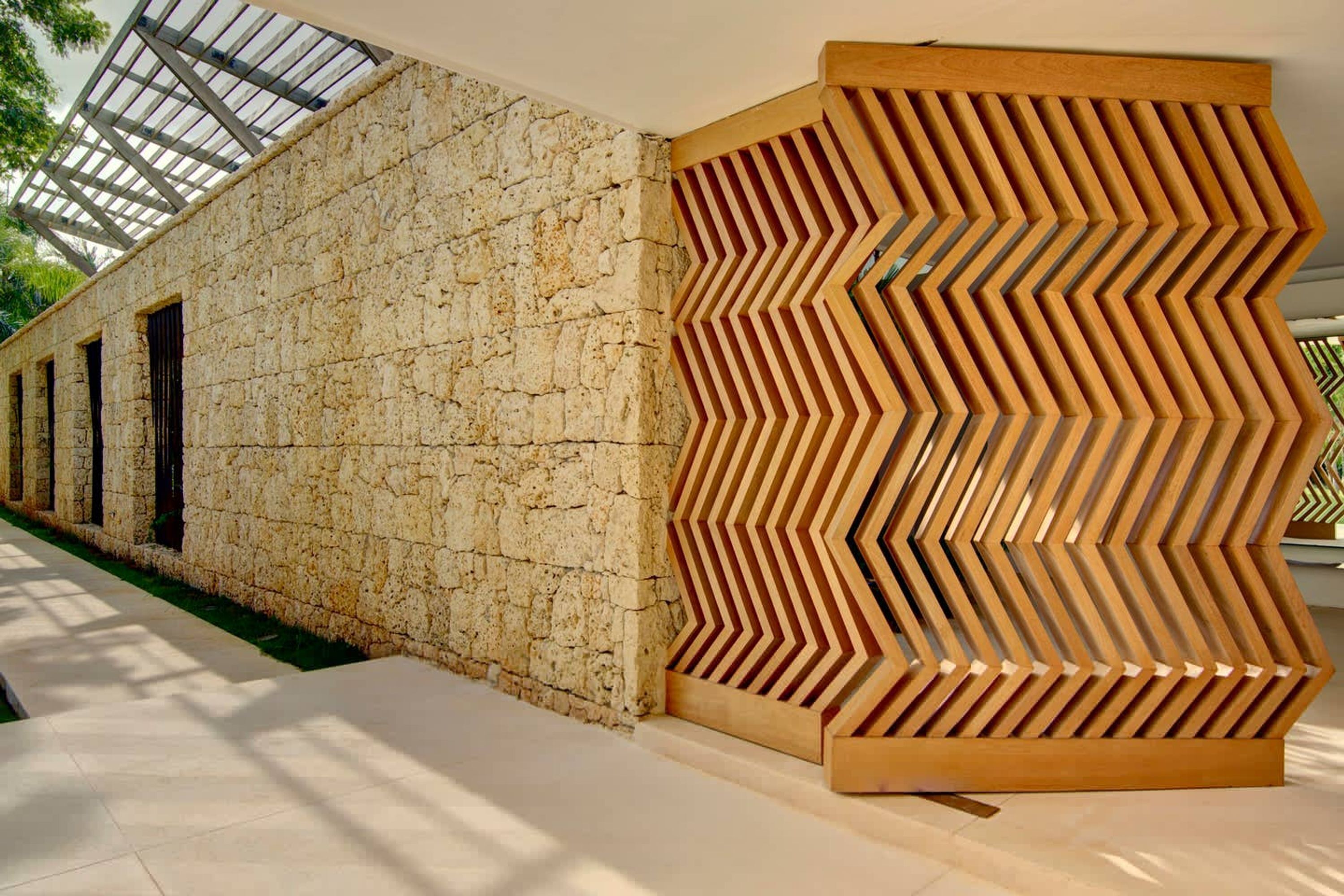 A modern building with a stone facade and a wooden geometric panel.