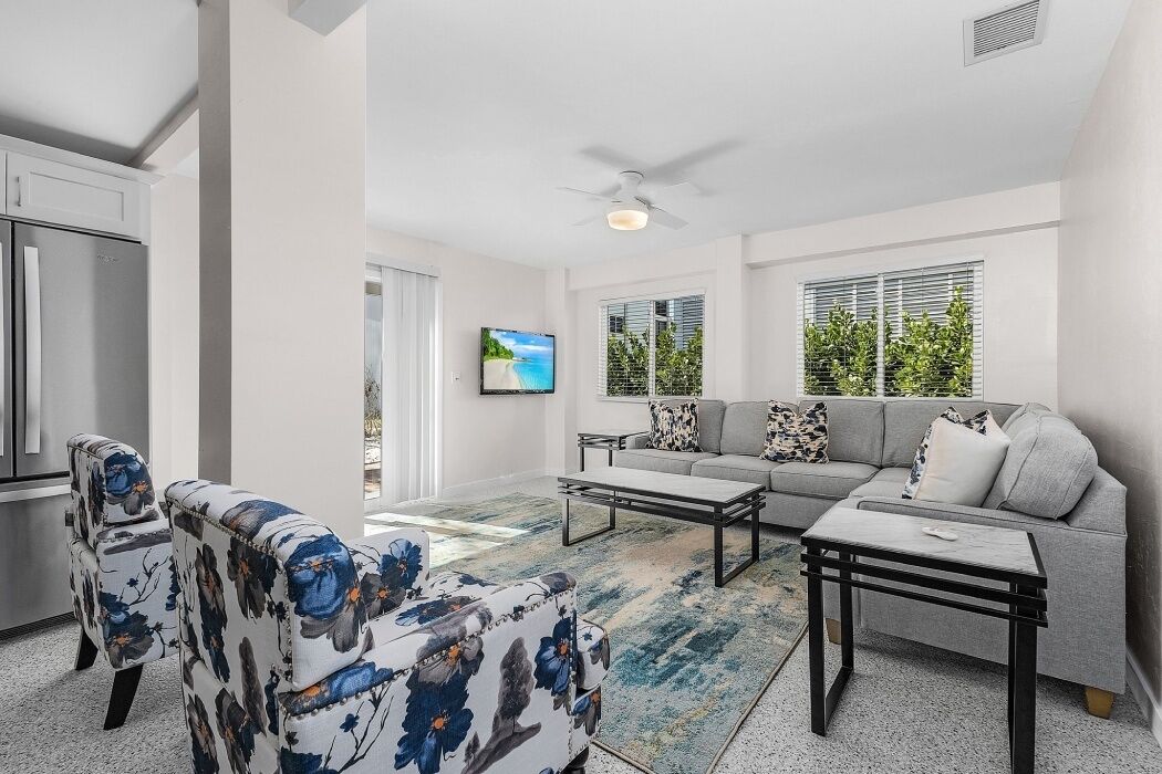 A modern living room with a grey sofa, a coffee table, and floral-patterned chairs.