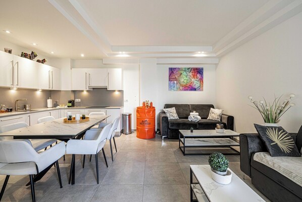Eine moderne Wohnung mit Essbereich, Küche, Wohnzimmer und einem farbenfrohen, abstrakten Gemälde an der Wand.