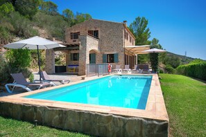 A stone building with a swimming pool, outdoor seating, and umbrellas. - Finca Lejania - Modern villa near Manacor with panoramic views (manacor)