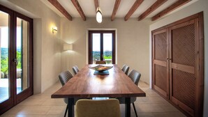 A dining area with a wooden table, chairs, and a view through large windows. - Finca Lejania - Modern villa near Manacor with panoramic views (manacor)
