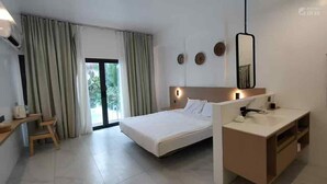 A modern hotel room with a bed, bedside table, and a desk with a chair. - Belle Homes (Panglao)