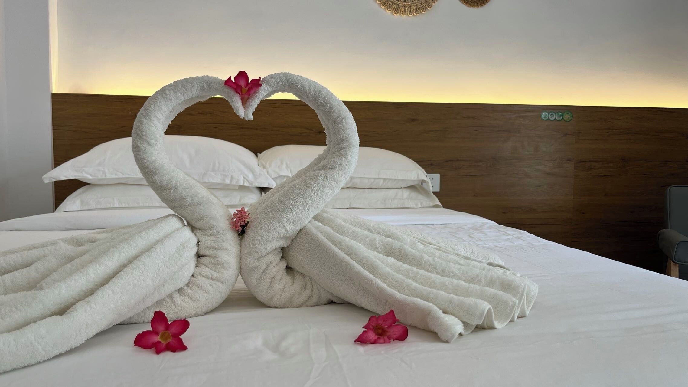 A bed with white linens and a decorative swan towel arrangement.