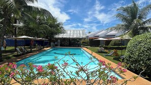 A swimming pool surrounded by palm trees and lounge chairs. - Belle Homes (Panglao)