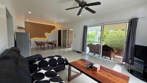 A modern living room with a black sofa, a wooden coffee table, and a ceiling fan. - Belle Homes (Panglao)