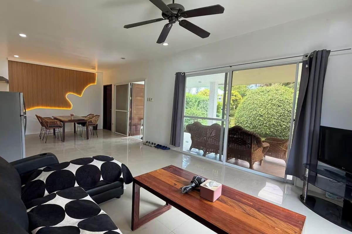 A modern living room with a black sofa, a wooden coffee table, and a ceiling fan.