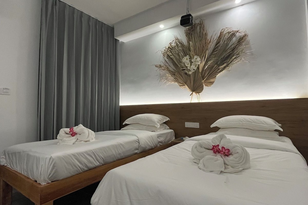 A hotel room with two beds, each with white linens and floral arrangements.