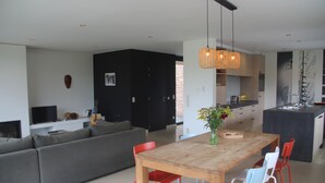Een moderne keuken met een eethoek, een bank en een televisie in de woonkamer.
