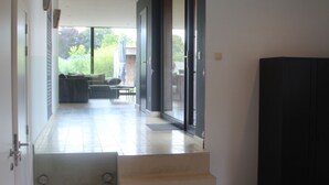 Een modern interieur met een trap naar een balkon, een donkere kast en uitzicht op het omliggende landschap.