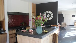 Een moderne keuken met houten kastjes, een zwart aanrecht, een grote klok en een bloemenvaas.