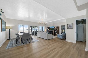A spacious living room with a dining area, a fireplace, and large windows overlooking a scenic view.