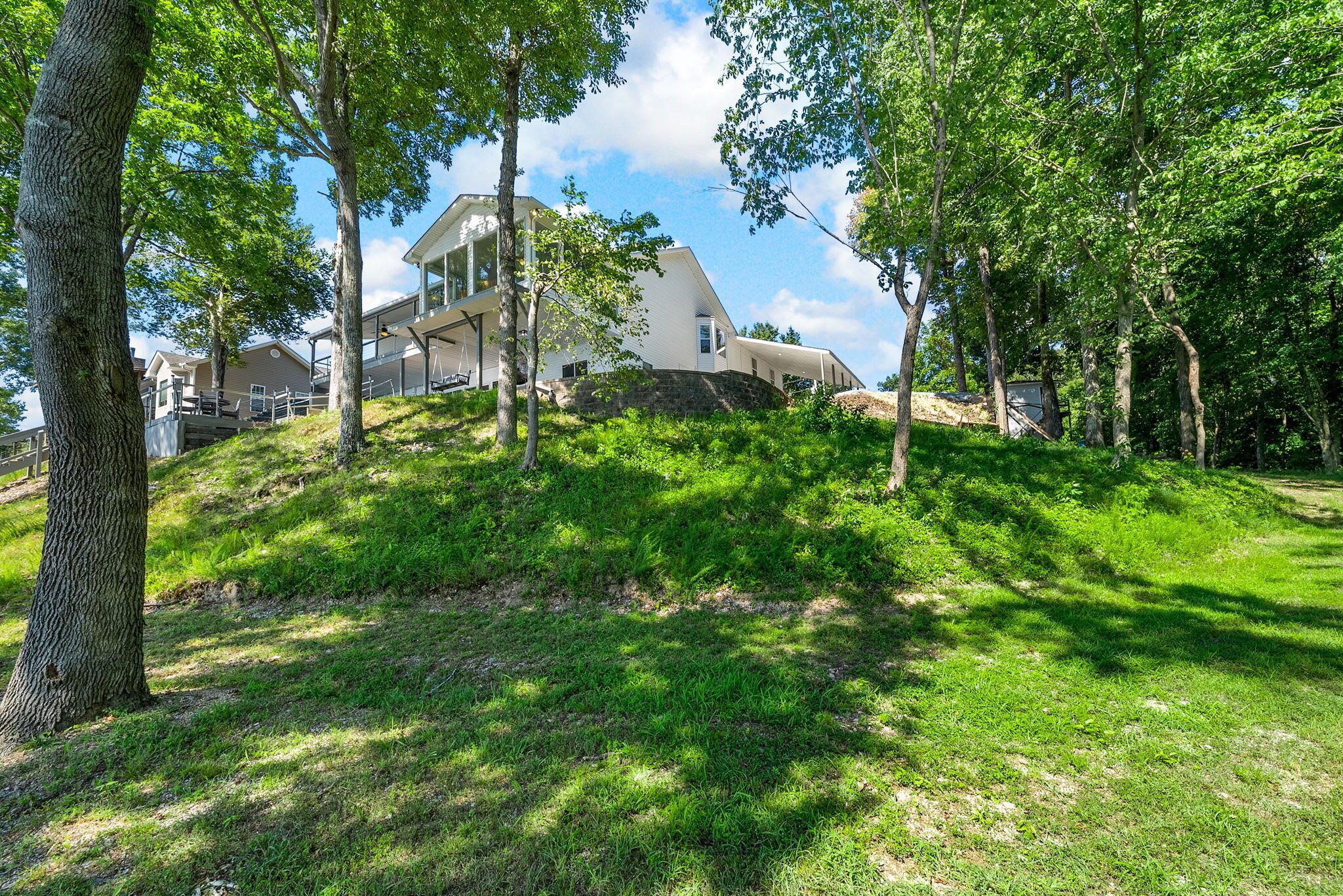 Ein modernes Haus mit einer großen Terrasse, umgeben von üppiger Bepflanzung und Bäumen.
