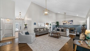 A spacious living room with a large window, a dining area, and a kitchen. - Bluebird Sanctuary • Serene Sunset Escape (Big Sandy)