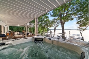 Un área de hidromasaje con terraza techada, mobiliario exterior y vista al agua.