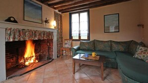 Una sala de estar acogedora con chimenea, un sofá verde y una mesa de centro de madera.