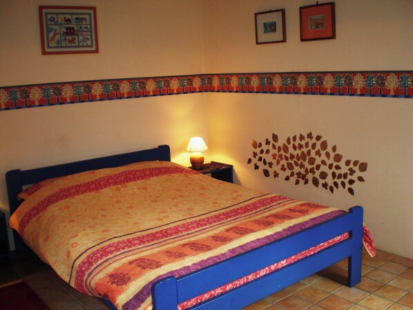 Un dormitorio con cama, mesita de noche, lámpara y un adorno en la pared.