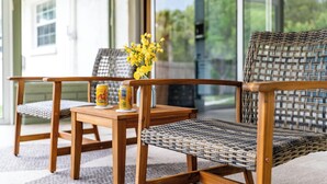 A wooden table with two wicker chairs, a vase with yellow flowers, and two cans of beer. - BayBreeze Cottage • Family-Friendly • Sleeps 6-8 • Near SRQ, Ringling & Beaches (Sarasota)