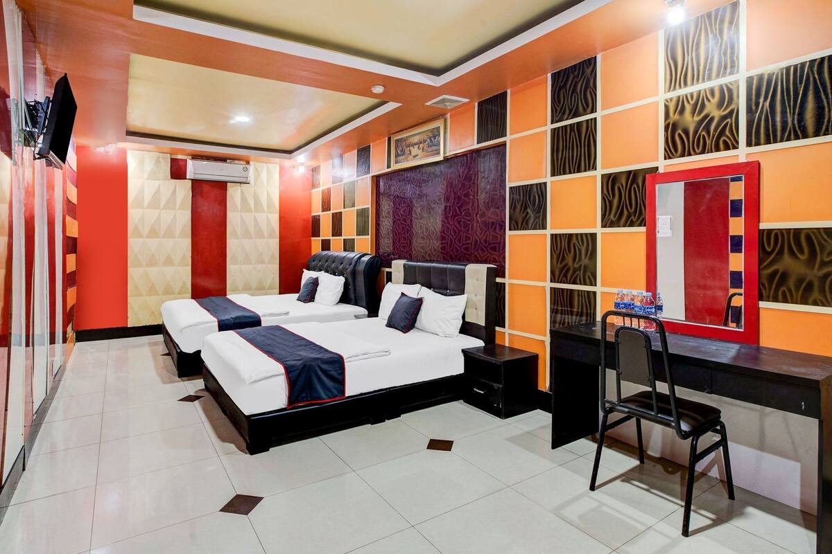 A hotel room with a large bed, a desk, and a chair.