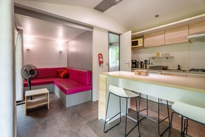 A modern kitchen with a bar area, a red sofa, and a small table. - Apartment 'Lydia's Mobilhome' with Shared Pool, Private Terrace and Garden (Boofzheim)