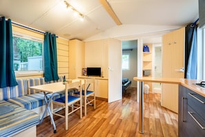 A compact kitchen with a dining area, a TV, and a window with curtains.