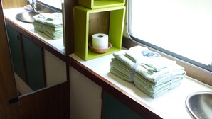 A compact bathroom with a toilet, sink, and green storage shelves. - Calm overnight aboard the JAVA boat, 30 minutes from PAL, disconnection guaranteed! (Luneau)