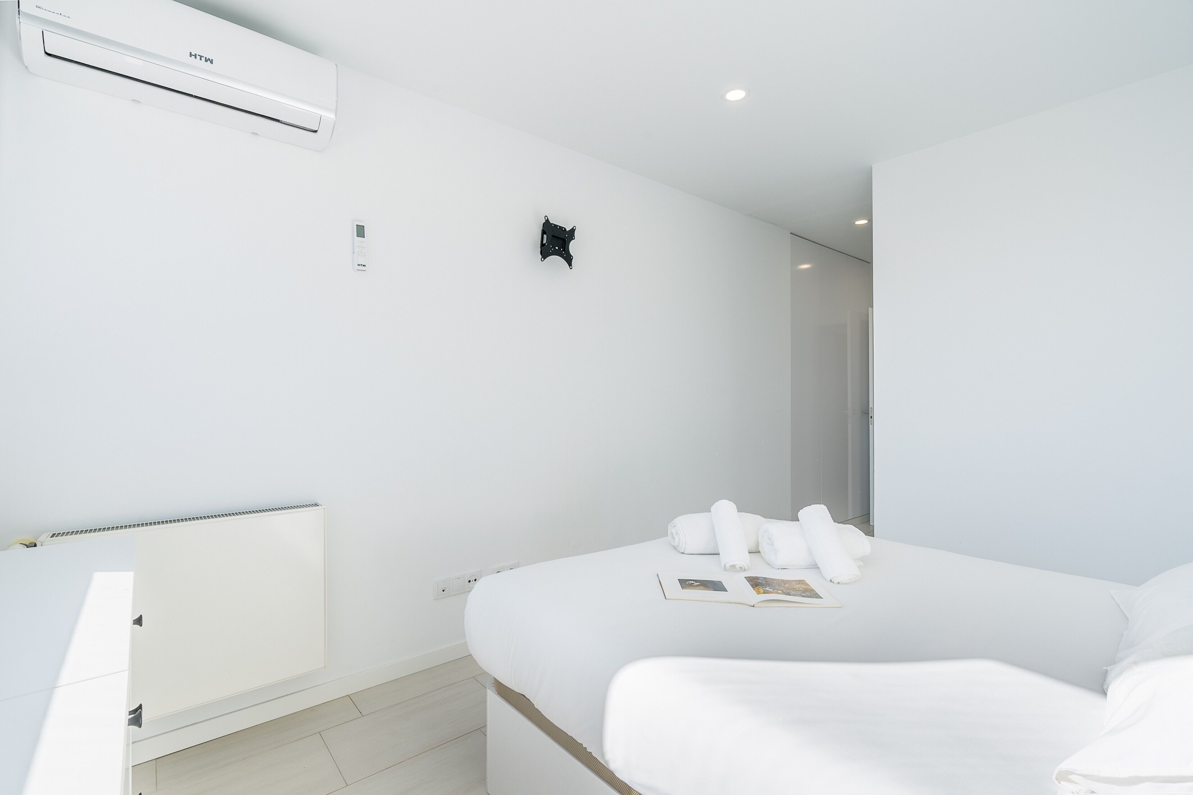 Une chambre d’hôtel équipée d’un lit, d’un radiateur, d’un climatiseur et d’un thermostat fixé au mur.